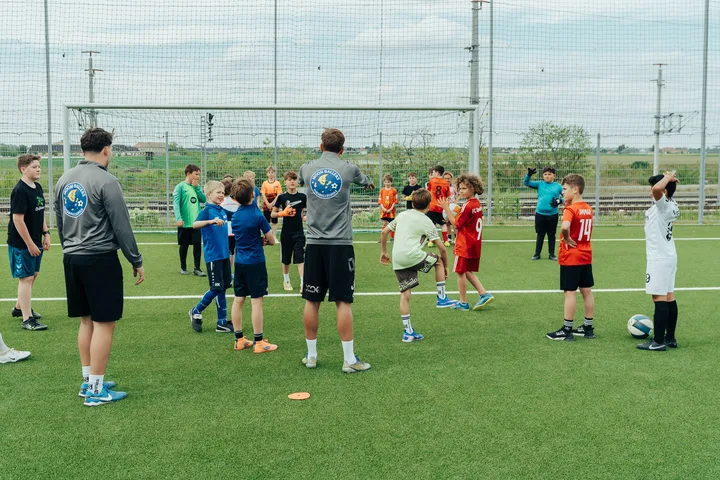 Kinder beim gemeinsamen Fußballtraining mit dem Trainer